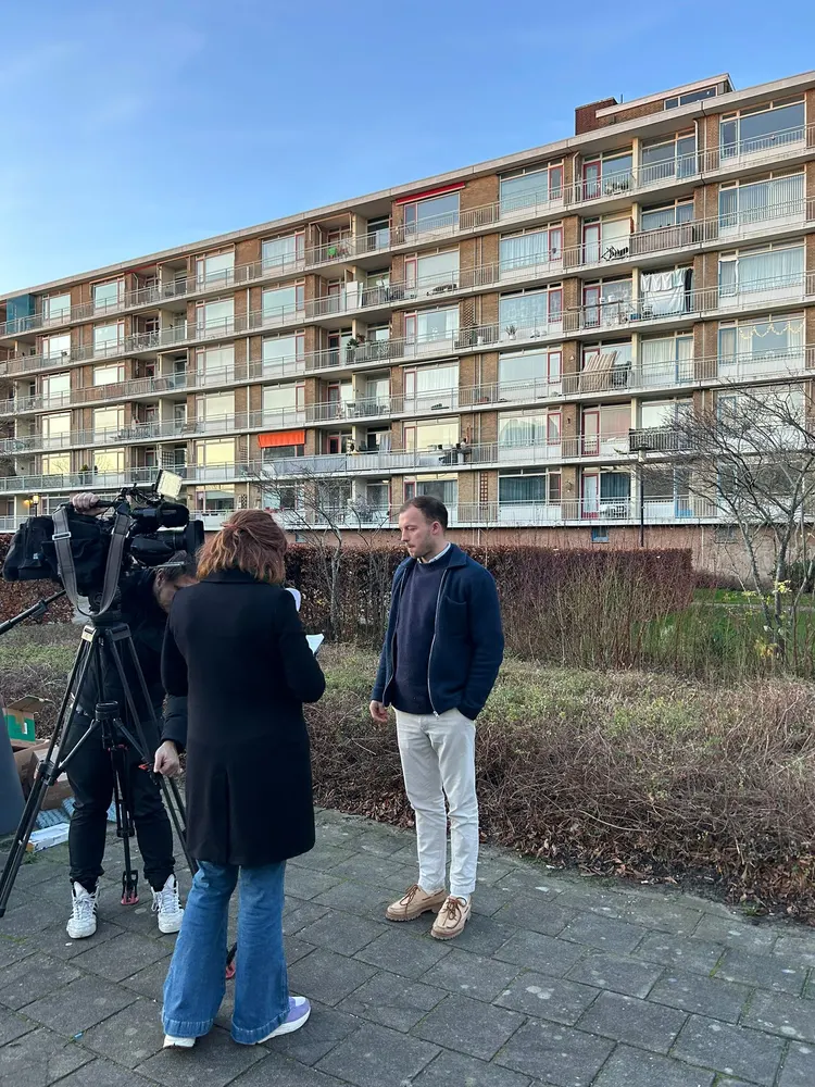 Een groep bekijkt een woongebouw van buiten, in de winter