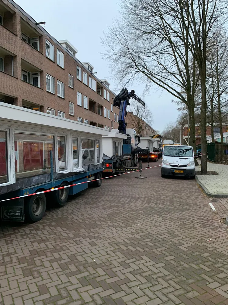 Bouwmateriaal op een vrachtwagen in de straat, naast het gebouw waar gewerkt wordt