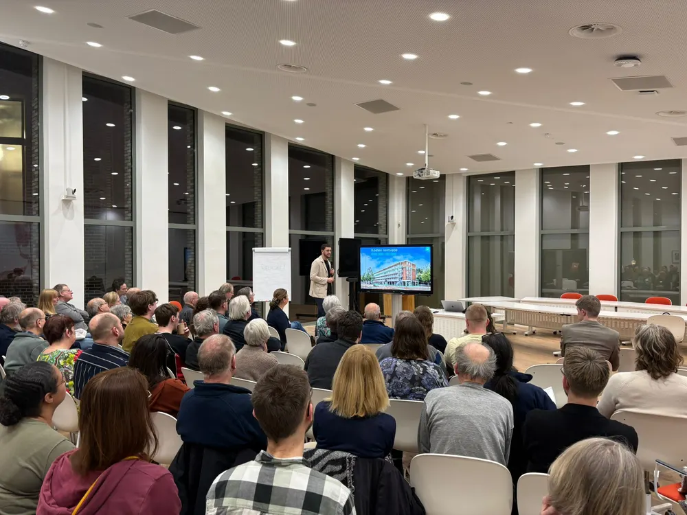 Een informatieavond in een volle zaal, met de presentatie op het scherm