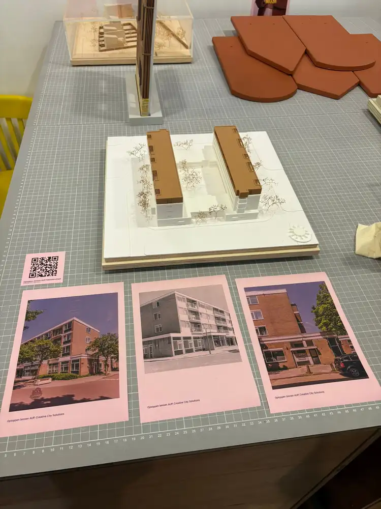Materiaalmonsters van hout naast een maquette en gedrukte rapporten op tafel