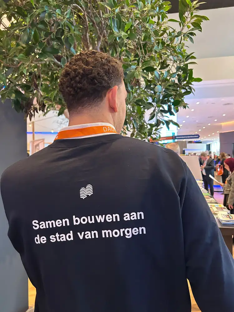 De rug van een trui met de tekst: samen bouwen aan de stad van morgen